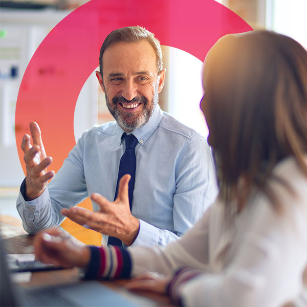 Homepage | Highlights image | Smiling male Mortgage broker at desk talking with a female client with Mortgage Brain angled gradient element behind